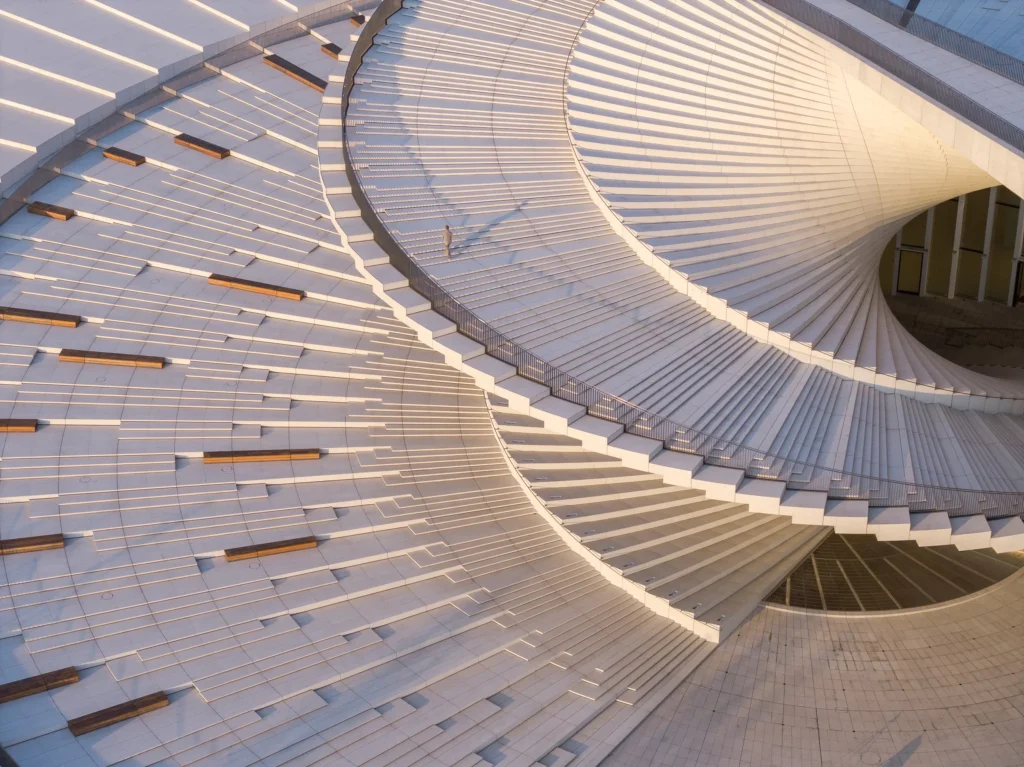 Aerial close-up of the spiraling white roof terrace with wooden benches and a single person walking