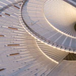 Aerial close-up of the spiraling white roof terrace with wooden benches and a single person walking