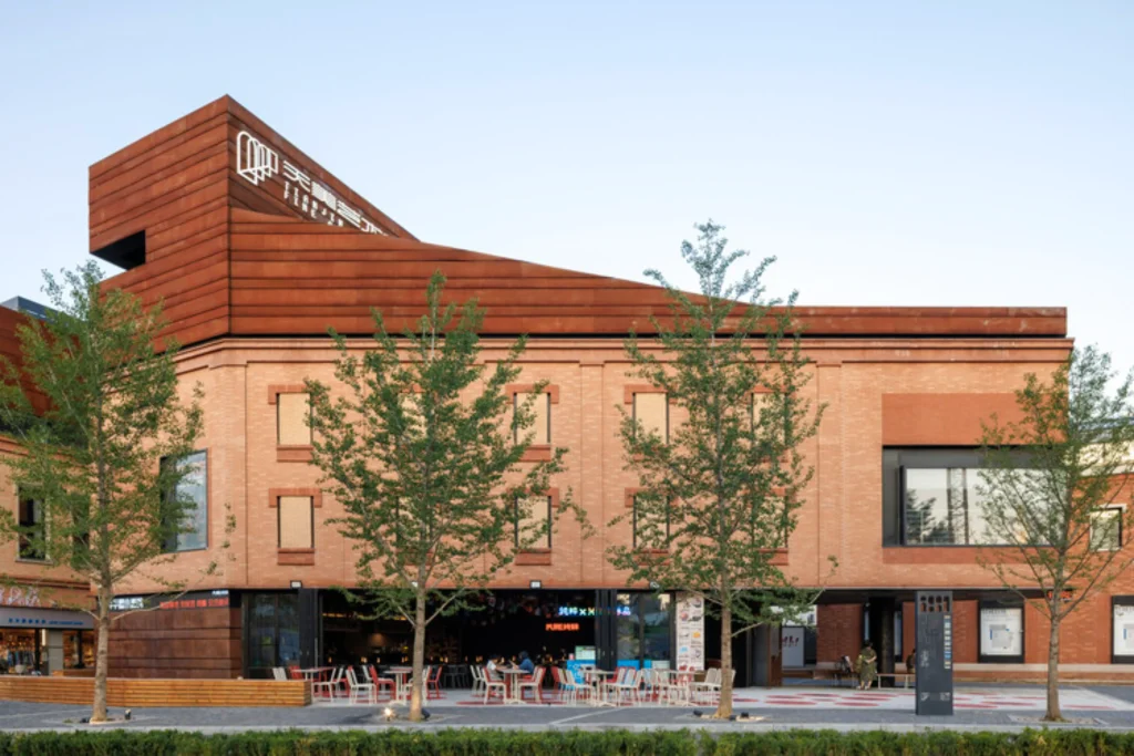Mixed brick and corten steel building with outdoor seating and café terrace at ground level