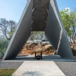 Concrete pyre structure formed by two large angled planes rising over a central fire grate, labelled Divya Sthal