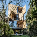 House with large shutters swung open on multiple levels, people visible on the floors and in the garden with a dog