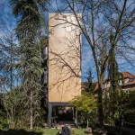Side view of the narrow plywood tower on steel legs, with a person and dog on the lawn