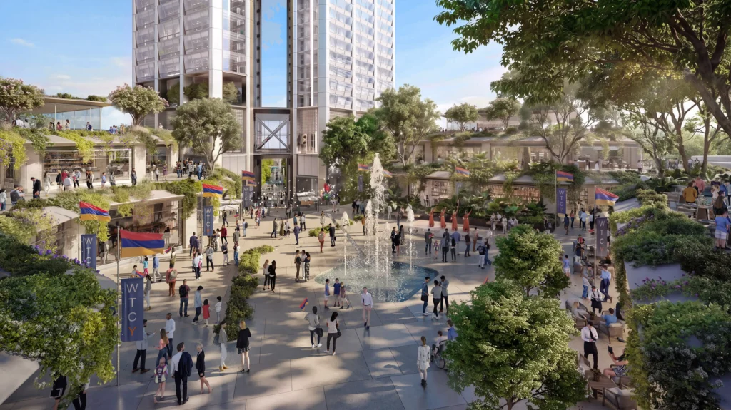 Lively public plaza at the base of the twin towers with a central fountain, trees, outdoor seating and people gathering under Armenian flags