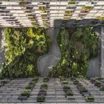 Aerial view of a dense green courtyard with winding paths between two multi-storey residential buildings