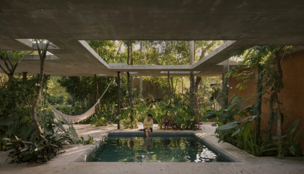 XIV BIAU Opens in Brasília Under Theme Caring for Life_Covered concrete outdoor room with a small pool, hammock and dense tropical planting, a person seated at the water’s edge