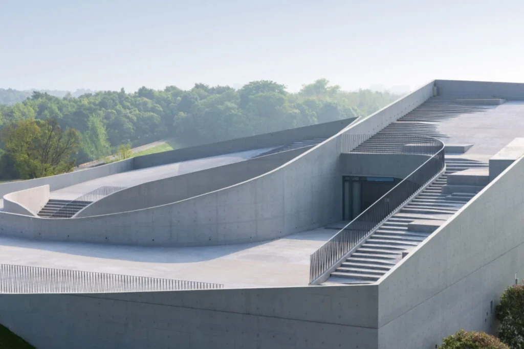 Detailed view of the sculptural concrete roofscape with curved stairs, ramps and railings under soft daylight