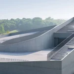 Detailed view of the sculptural concrete roofscape with curved stairs, ramps and railings under soft daylight